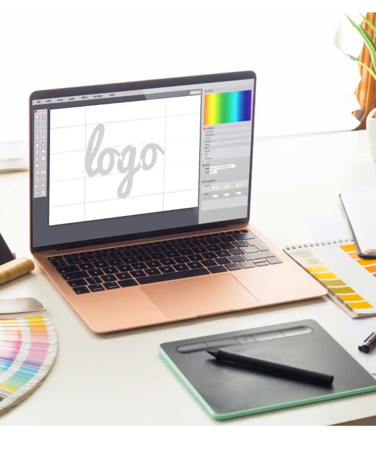 Laptop mit Grafiksoftware, daneben Farbpalette und Grafiktablett.